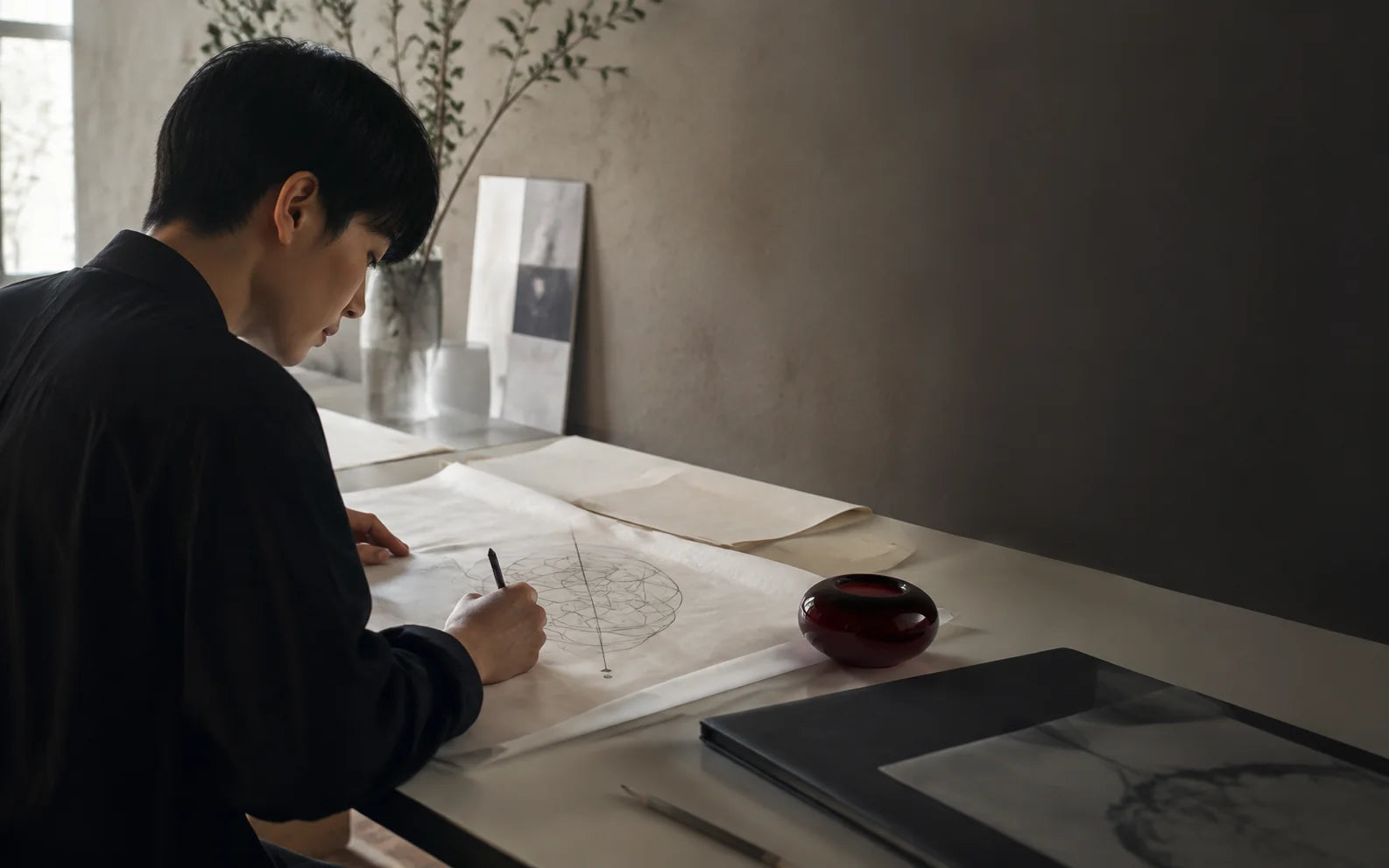 An artist developing an original fine-line drawing at a studio desk