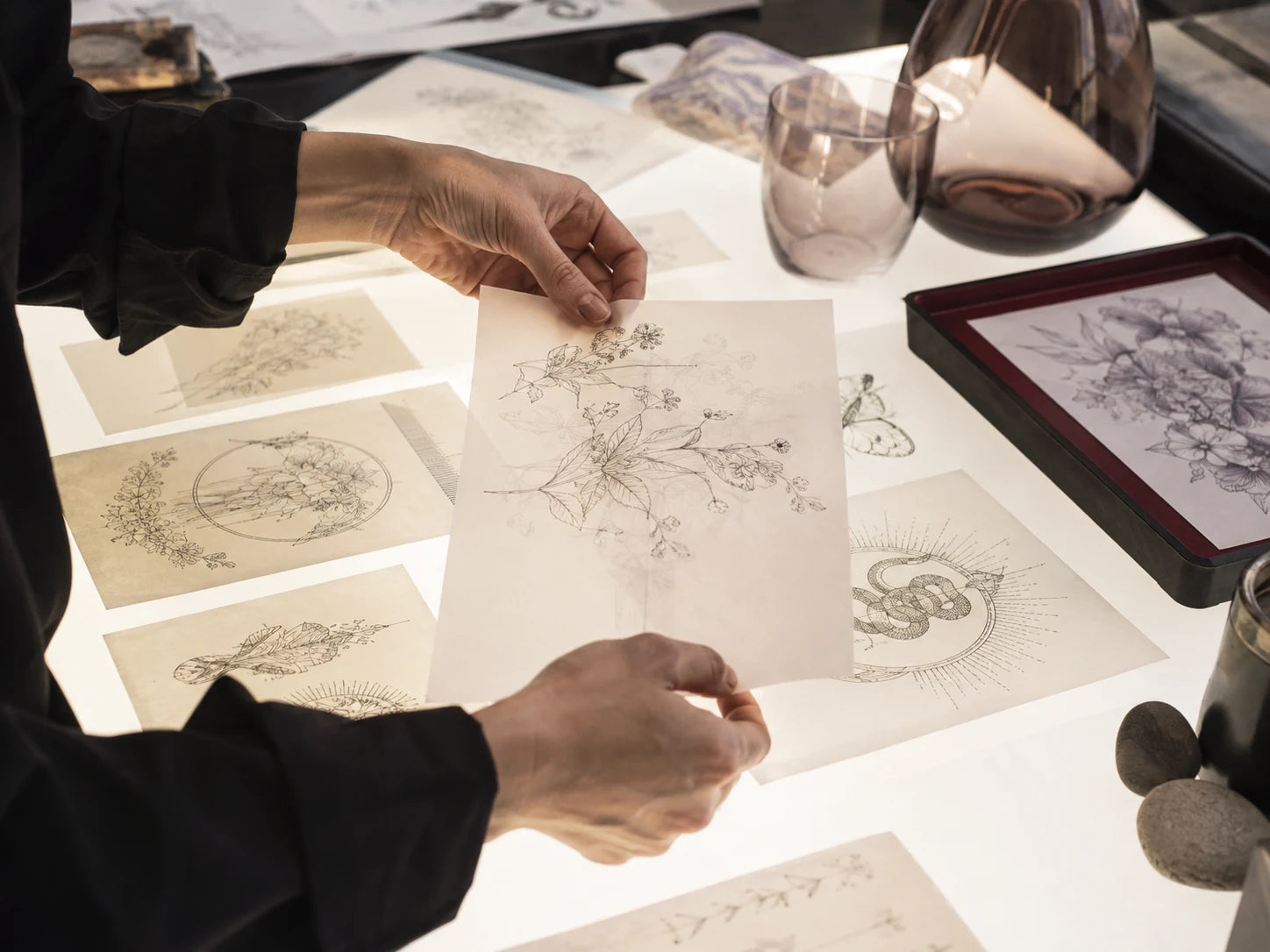Tattoo artwork reviewed by hand on a studio light table