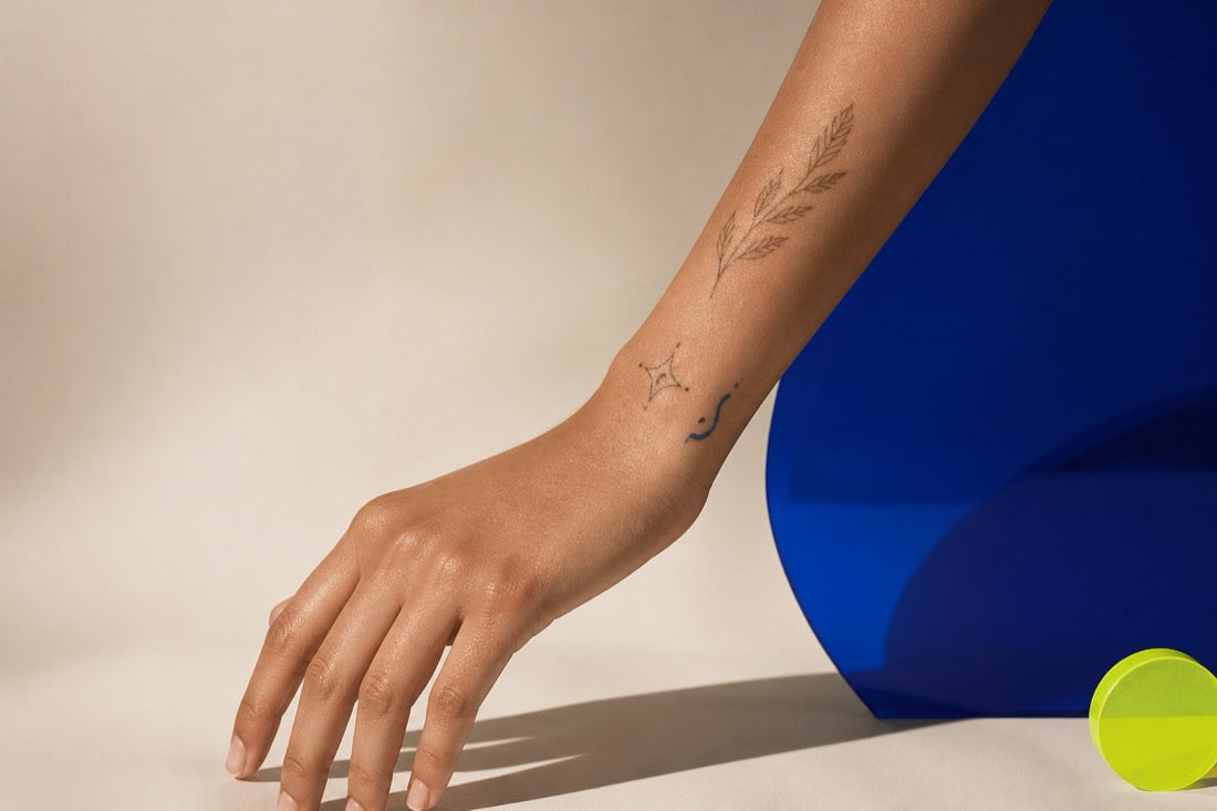 Fine-line temporary tattoos on a forearm in a dark studio setting